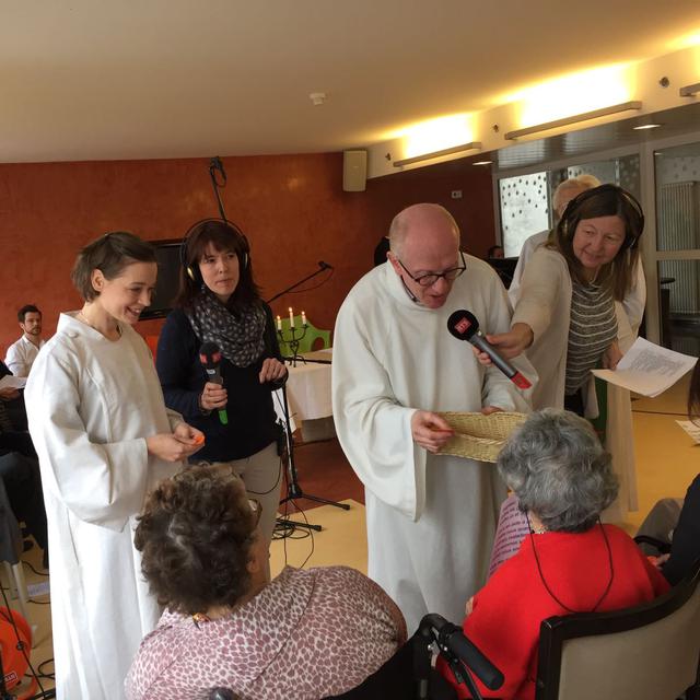 Le pasteur Dominique Troilo et l'assistante pastorale catholique Valdone Kupsiene distribuent des versets bibliques aux personnes âgées. [Anne-Catherine Reymond]