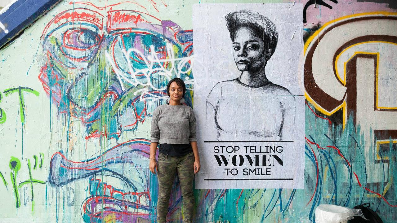 Tatyana Fazlalizedeh devant un des portraits de la série "Stop telling women to smile". [DR]