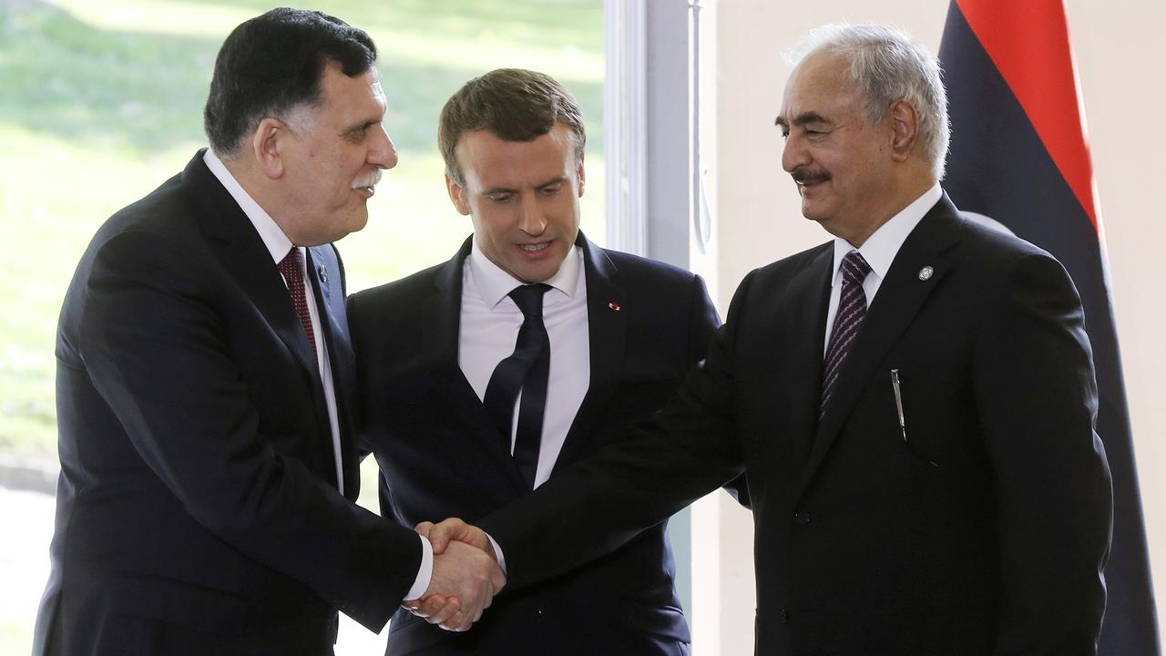 Le Premier ministre du gouvernement libyen d'union nationale Fayez al-Sarraj (à gauche) et le général Khalifa Haftar (à droite) se serrent la main, sous les yeux du président français Emmanuel Macron. [AFP - Jacques Demarthou]