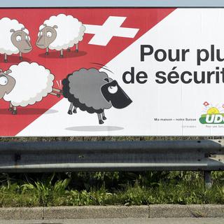 Une affiche de l'UDC placardée dans une rue genevoise pour la campagne des élections fédérales de 2007. La représentation du mouton noir expulsé provoquera un tollé au-delà des frontières nationales. [Salvatore Di Nolfi, 2007]