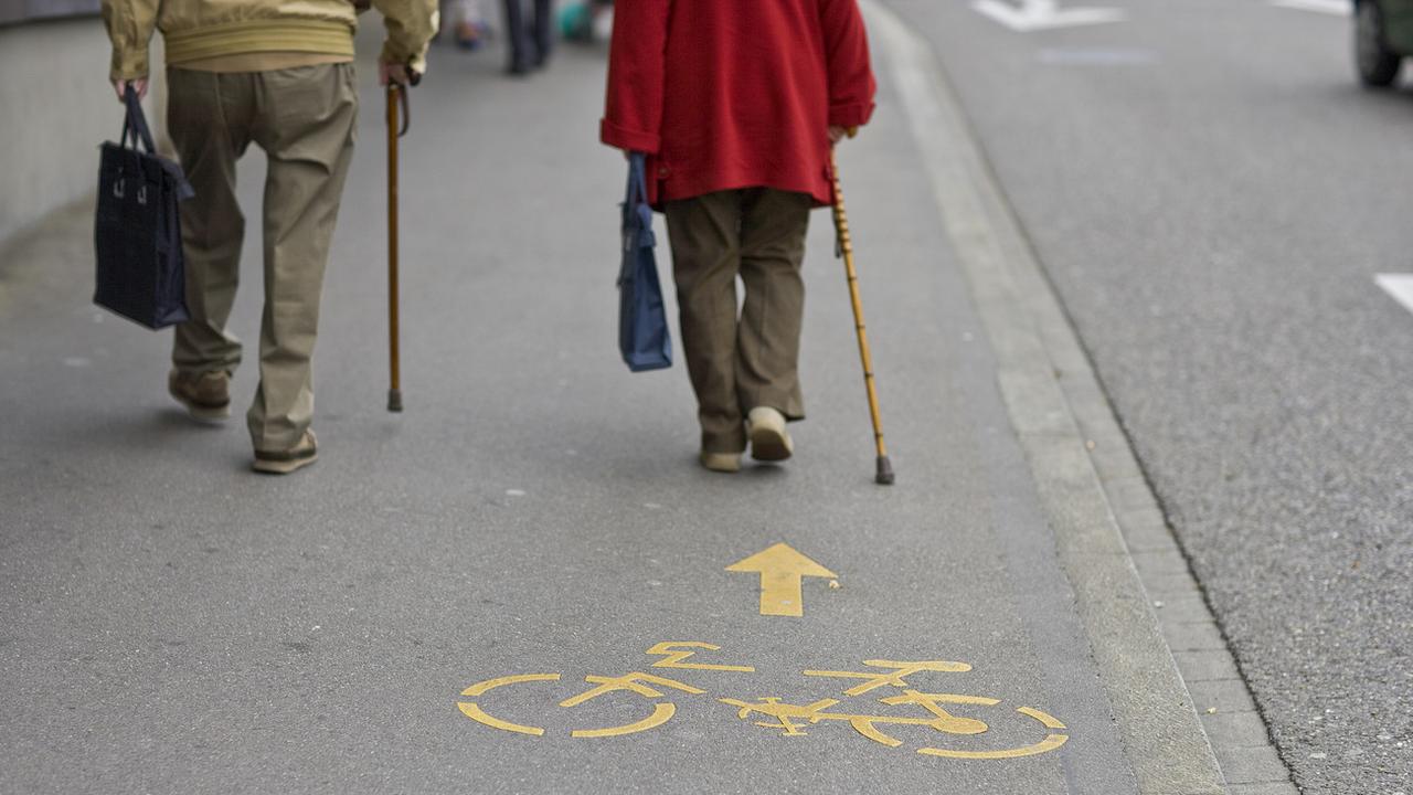 Deux personnes âgées marchent sur un trottoir à Zurich. [Keystone - Gaetan Bally]