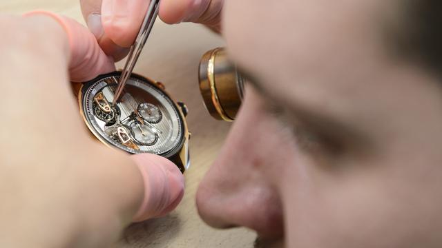 Un horloger au travail dans une usine à La Chaux-de-Fonds. [Keystone - Jean-Christophe Bott]