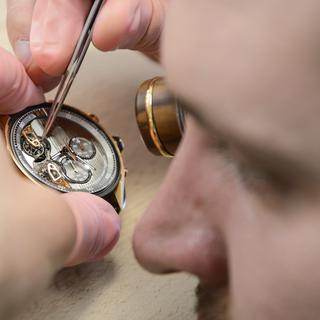 Un horloger au travail dans une usine à La Chaux-de-Fonds. [Keystone - Jean-Christophe Bott]