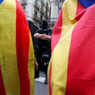 Militants séparatistes et un policier catalan, devant les locaux de la Police nationale à Barcelone. [Reuters - Yves Herman]