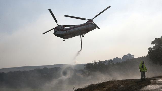 Un hélicoptère arrose la région de Napa, en Californie, ravagée par les flammes. [Keystone - AP Photo/Rich Pedroncelli]