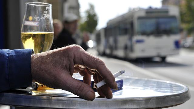 Un homme fume une cigarette sur une terrasse d'un café (image d'illustration). [Keystone - Dominic Favre]