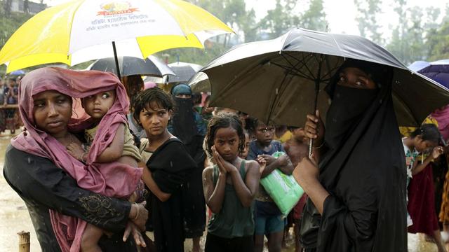Les réfugiés Rohingya font la file d'attente sous la pluie pour recevoir des biens de première nécessité près d'un centre à Balukhali, au Bangladesh, le 12 octobre 2017 [KEYSTONE - ABIR ABDULLAH]
