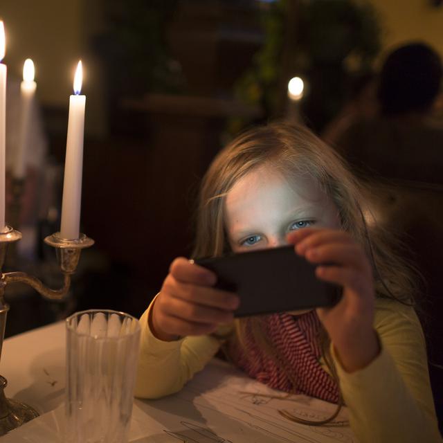 Une enfant joue avec un smartphone dans un restaurant. [Keystone - Gaetan Bally]