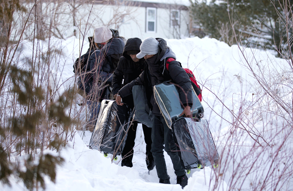 Une famille de migrants traversent la frontière entre les Etats-Unis et le Canada. [Reuters - Christinne Muschi]