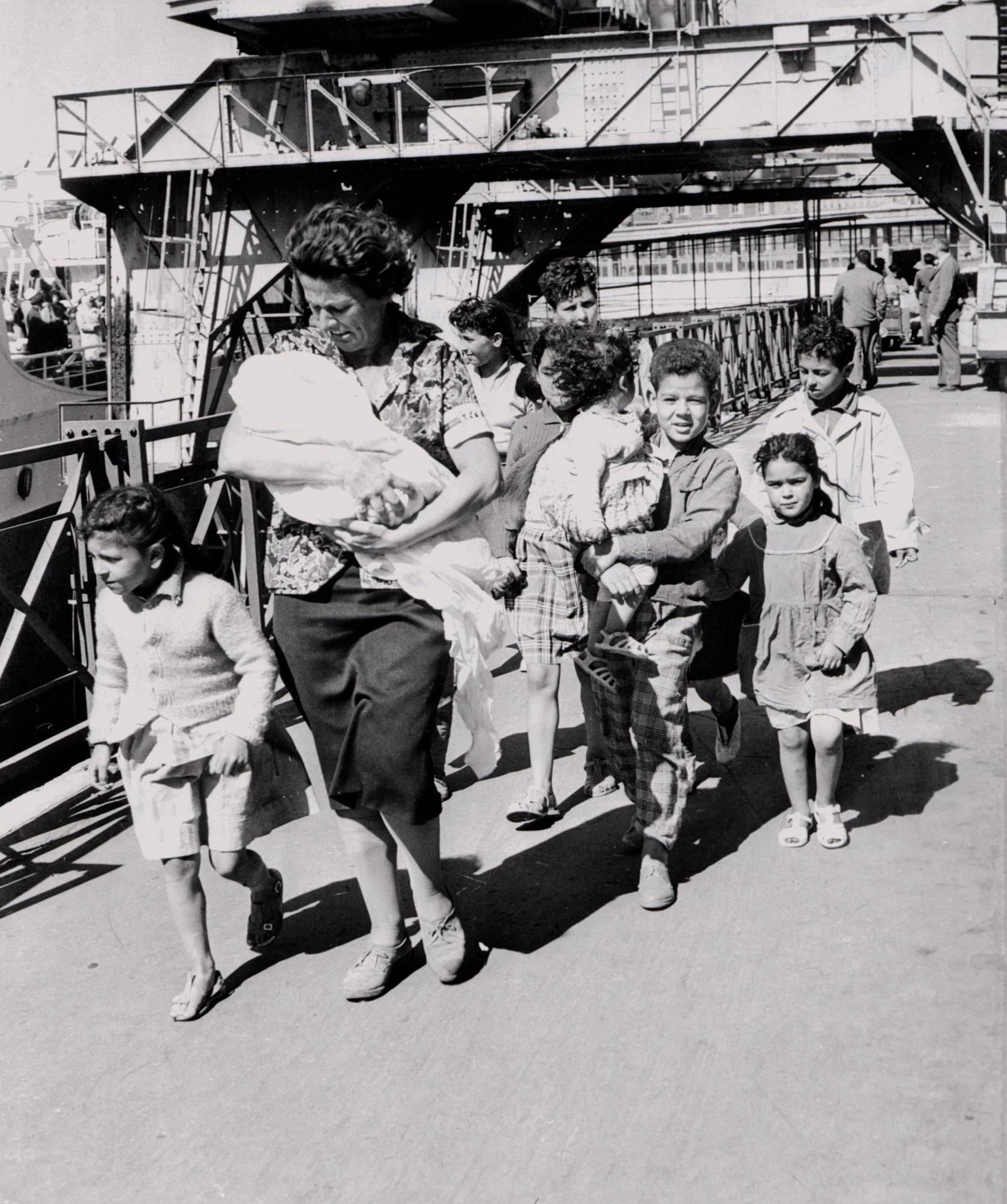 Une femme et ses enfants désireux de gagner la métropole viennent de débarquer du "Ville d'Oran" à Marseille le 26 mai 1962 comme de nombreux réfugiés notamment des Européens d'Algérie (pieds noirs) et des familles de harkis qui continuent d'affluer vers la France depuis la signature des accords d'Evian. [AFP]