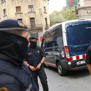 Des policiers emmènent des suspects arrêtés à Ripoll, au nord de Barcelone, en lien avec les attentats qui ont ensanglanté la Catalogne. [Keystone - Francisco Seco]