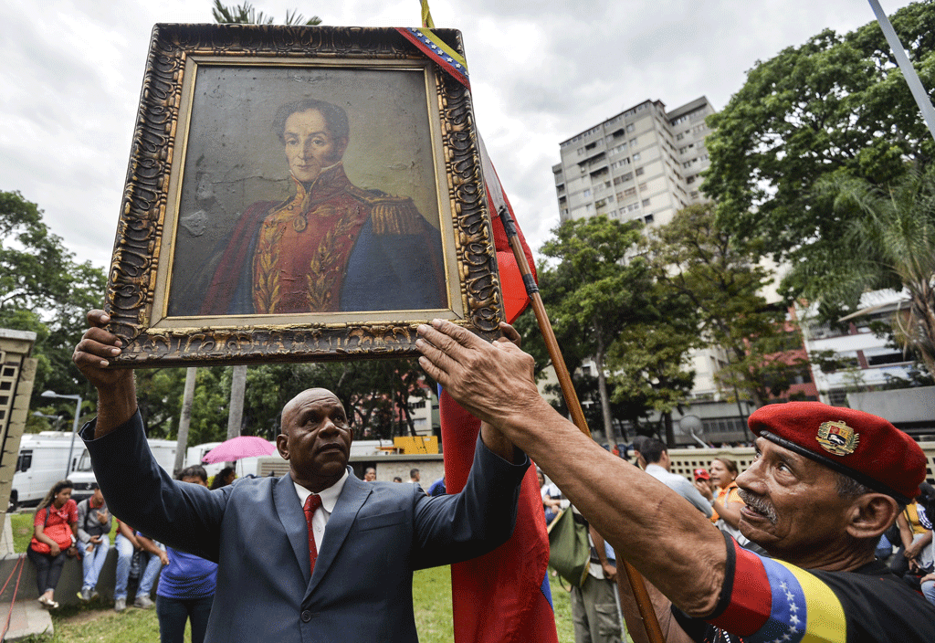 Un supporter du président Nicolas Maduro avec une peinture de Simon Bolivar. [AFP - Luis Robayo]