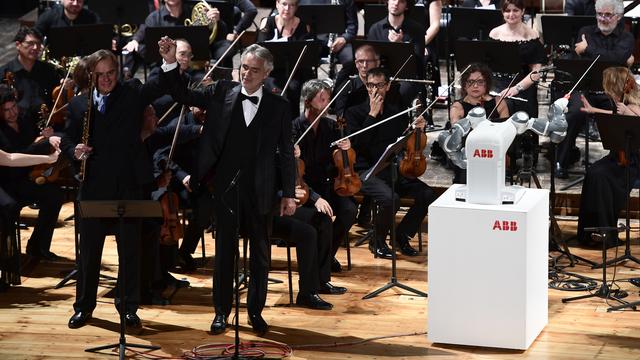 Le robot YuMi devant l'orchestre philharmonique de Lucques et aux côtés du ténor italien Andrea Bocelli. [AFP - MIGUEL MEDINA]