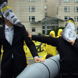 Des activistes de l'ICAN manifestent à Berlin avec des masques de Kim Jong-un et de Donald Trump. [Keystone - Britta Pedersen]