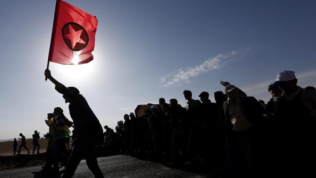 Un militant brandit le drapeau du PKK (Parti des Travailleurs du Kurdistan) lors des funérailles d'une combattante kurde dans la ville syrienne de Kobané. [Sedat Suna/Keystone]