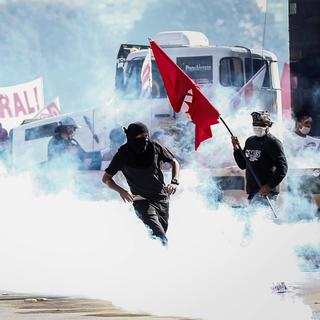Des manifestants au milieu des fumigènes des forces de police lors d'un rassemblement contre le président Temer à Brasilia. [Keystone - Fernando Bizerra Jr.]