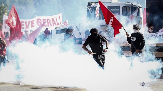 Des manifestants au milieu des fumigènes des forces de police lors d'un rassemblement contre le président Temer à Brasilia. [Keystone - Fernando Bizerra Jr.]