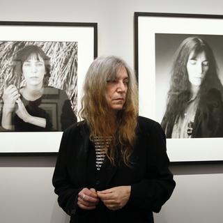 La chanteuse Patti Smith devant deux de ses portraits réalisés par le photographe Robert Mapplethorpe, lors d'une exposition au Grand Palais à Paris en mars 2014. [PATRICK KOVARIK]