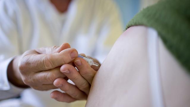 Une patiente se fait vacciner dans un cabinet médical du canton de Zurich. [Keystone - Gaëtan Bally]