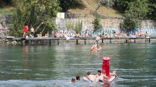 Des nageurs s'agrippent à un îlot sécuritaire flottant lors des journées de prévention sur la baignade dans le Rhône à Genève. [Keystone - Anthony Anex]