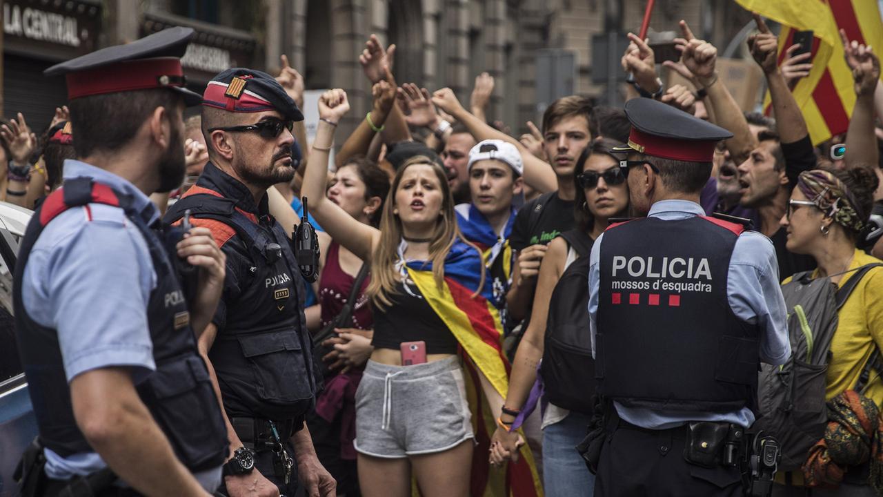 Des manifestants encadrés par la police catalane mardi lors de la grève générale. [AP Photo/Keystone - Santi Palacios]