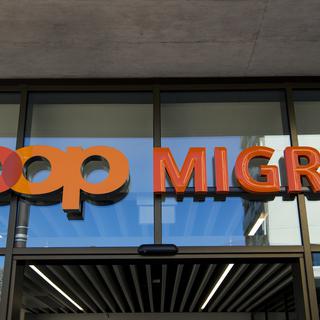 Le logo de la Coop et le logo de la Migros côte à côte sur un bâtiment commercial commun sur la place de la Sallaz à Lausanne. [Keystone - Jean-Cristophe Bott]