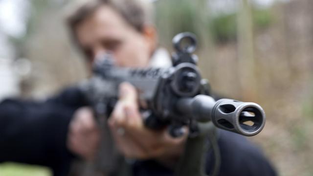 Un homme tient un fusil d'assaut de l'armée suisse. [Keystone - Martin Ruetschi]