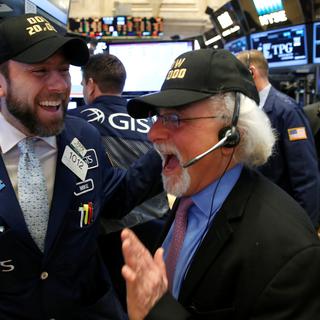 Des traders du New York Stock Exchange (NYSE), avec des casquettes "DOW 20'000" visiblement ravis de voir l'indice vedette de Wall Street franchir la barre des 20'000 points à New York, le 25 janvier 2017. [reuters - Brendan McDermid]