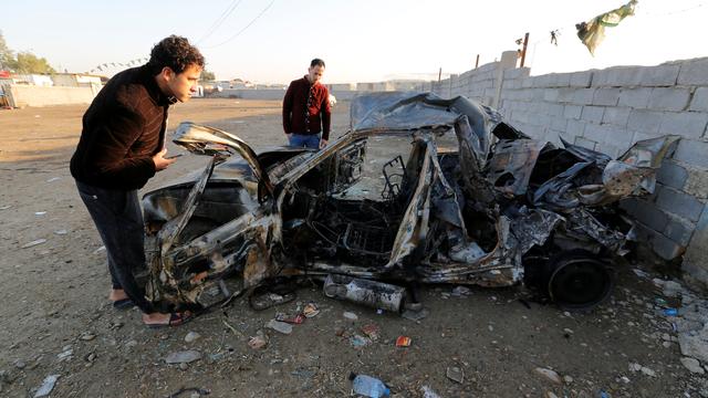 Men look at the wreckage of a burnt car after a suicide bomber detonated a pick-up truck on Wednesday in Sadr City, a heavily populated poor Shi'ite suburb of Baghdad, Iraq, February 16, 2017. REUTERS/Wissm al-Okili [REUTERS - Wissm al-Okili]