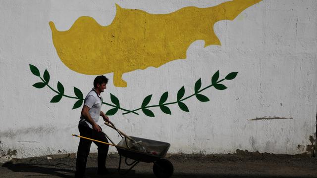 Un homme et sa brouette devant une fresque murale représentant l'île de Chypre. [Reuters - Yiannis Kourtoglou]