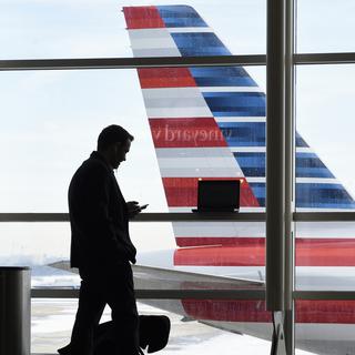 Un passager devant un avion de la compagnie American Airlines à l'aéroport Ronald Reagan de Washington, aux Etats-Unis (image d'illustration). [Keystone - AP Photo/Susan Walsh]