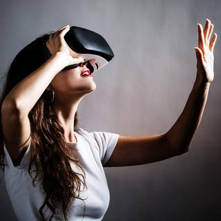 Une jeune femme teste un casque de réalité virtuelle. [Fotolia - Tierney]