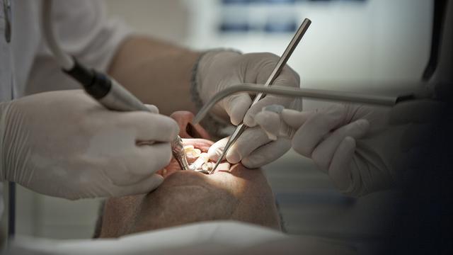 Un dentiste inspecte les dents d'un patient. [Keystone - Gaetan Bally]