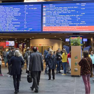 Des usagers des CFF guettant les informations et les retards de train dans le hall principal de la gare de Berne, mercredi 29 mars. [Keystone - Lukas Lehmann]