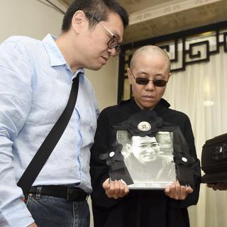 Liu Xia avec le portrait de son mari lors de ses obsèques, le 15 juillet dernier. [Keystone - Shenyang Municipal Information Office via AP]
