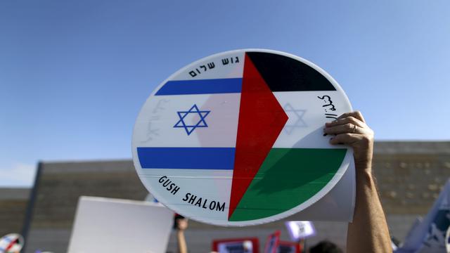 Un manifestant tient un panneau avec le drapeau de la Palestine et celui d'Israël. [Reuters - Ammar Awad]