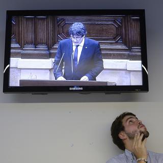 Un homme regarde le discours de Carles Puigdemont à la télévision le 10 octobre 2017. [AFP - Josep Lago]