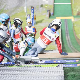 Des enfants s'entraînent au saut à ski sur une piste à Kandersteg (BE). [Keystone - Urs Flueeler]