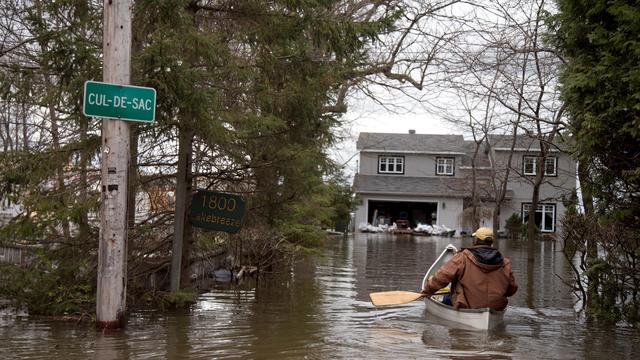 Un homme rame en direction de sa maison inondée, dans la ville de Deux-Montagnes, au Québec.