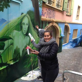 La coordinatrice de quartier, Caroline Juillerat, devant une partie de la fresque, rue du Neubourg à Neuchâtel. [RTS - Roger Guignard]