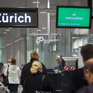 Des voyageurs au contrôle des passeports à l'aéroport de Zurich. [Keystone - Gaëtan Bally]