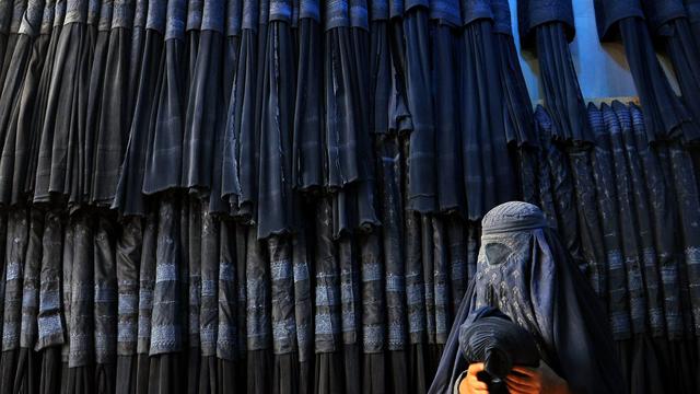 Une femme devant un magasin de burqa en Afghanistan. [Keystone - SAYED MUSTAFA]