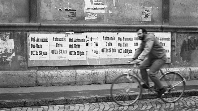 Un cycliste passe devant les affiches de la campagne pour l'autonomie jurassienne en 1974. [KEYSTONE / STR]