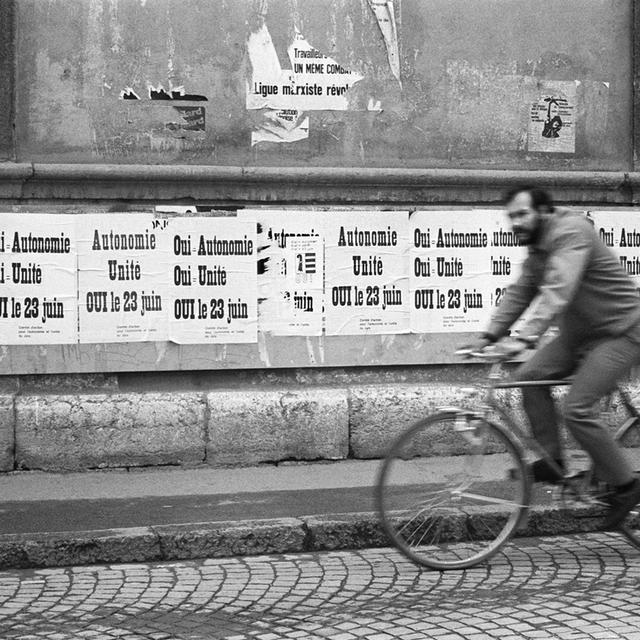 Un cycliste passe devant les affiches de la campagne pour l'autonomie jurassienne en 1974. [KEYSTONE / STR]