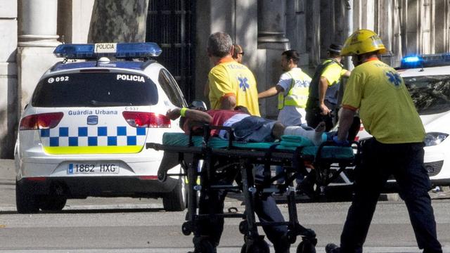 Un blessé évacué par les secours catalans sur l'avenue Las Ramblas. [Keystone - Quique Garcia]