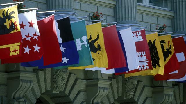 Les drapeaux des cantons sur la façade du Palais fédéral à Berne. [Keystone - Urs Flueeler]