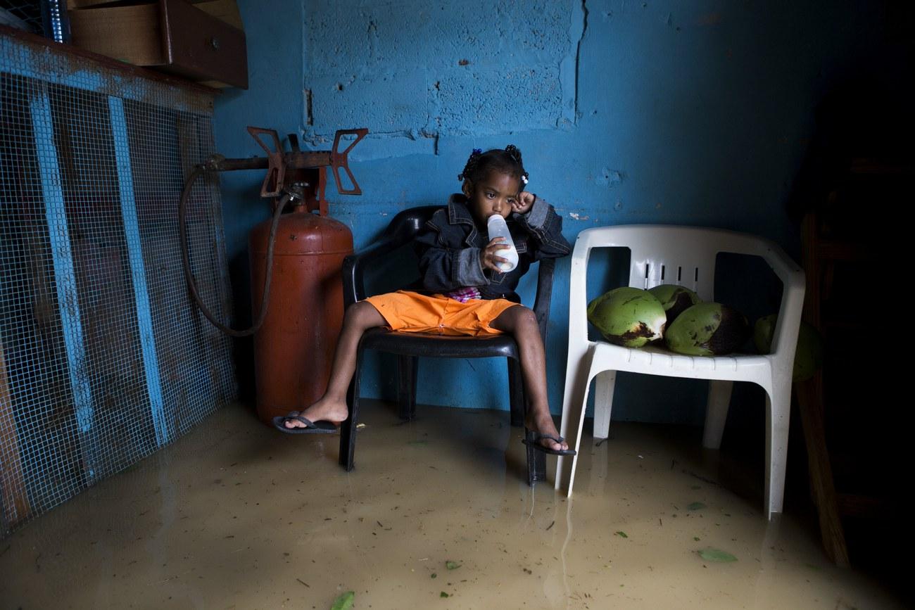 Une fillette boit du lait dans une chambre inondée après le passage de Maria en République dominicaine. [Keystone - ORLANDO BARRIA]