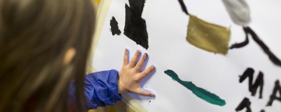 Une enfant fait de la peinture dans une garderie. [Keystone - Gaëtan Bally]