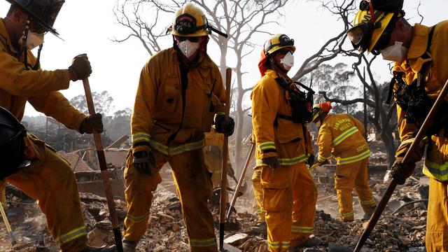 Des pompiers recherchent des effets personnels des habitants d'une maison détruite par les flammes, le 13 octobre 2017.