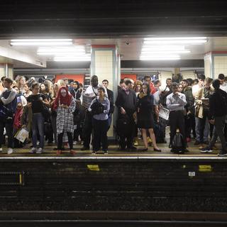 Des pendulaires attendent sur un quai du métro londonien. [Keystone - Facundo Arrizabalaga]